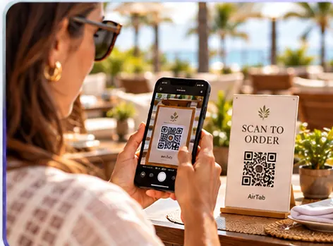 Guest scanning an AirTab QR code with her phone at a restaurant table